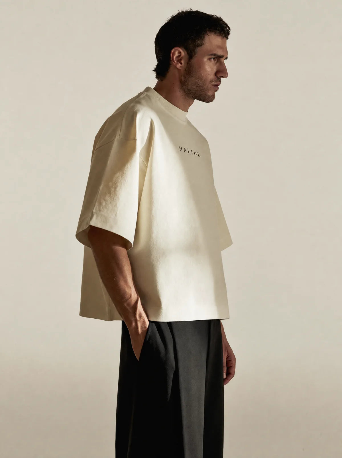 A man in an ivory heavyweight tee against a bone backdrop.